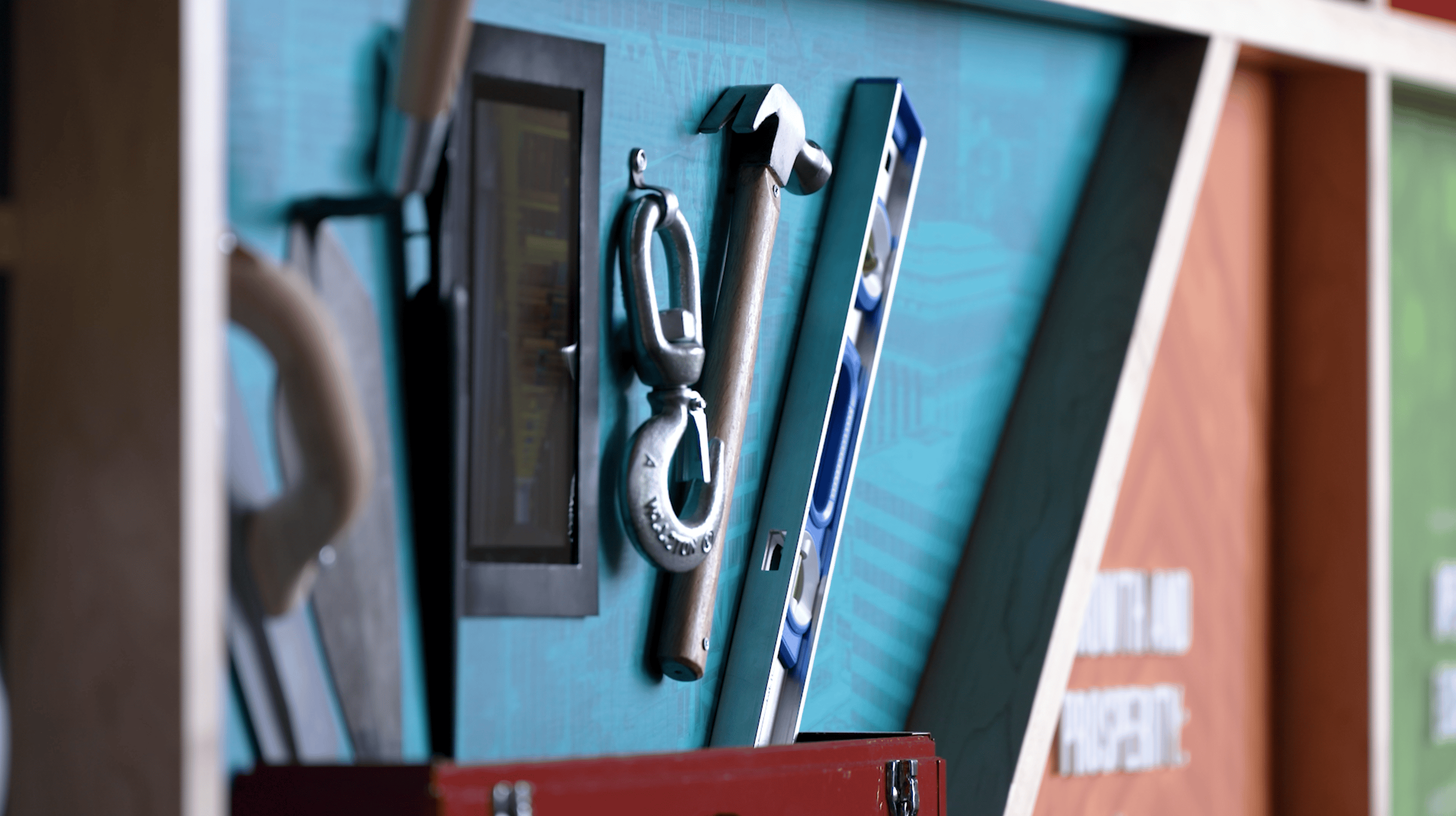 Display of construction tools and equipment in a branded Findorff toolbox setup by Thysse. The installation features a trowel, wrench, hammer, and level, mounted against a blueprint-themed backdrop as part of the facility branding project.